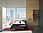 图中显示的是一个酒店房间，在大角窗前有一张床。墙壁和家具都使用了几种高质量的材料。