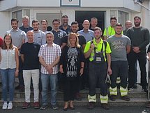 Absolventen Arnsberg Eine Gruppe von etwa 20 Auszubildenden und Ausbildern posiert vor einem Gebäude für ein Gruppenfoto