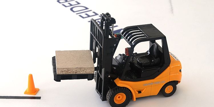 Man sieht einen Miniaturgabelstapler, welcher ein kleine Stück Holz um eine Pylone maneuvriert. 