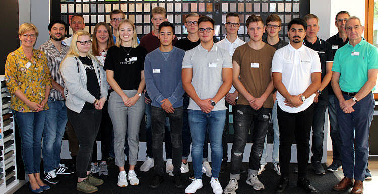 Ausbildungsstartgruppenfoto Gütersloh Man sieht etwa 20 Auszubildende und Ausbilder, welche in 3 Reihen für ein Gruppenfoto posieren.