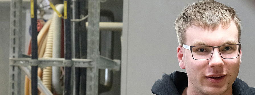 Ein junger Mann bedient einen Hebel in einer Fabrik